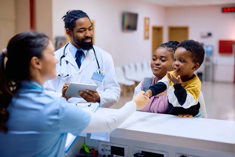 A family talking with staff at a hospital reception counter